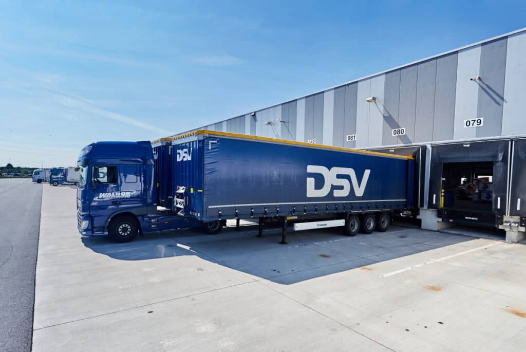 DSV lastbil ved en lagerbygning under logistikoperationer. Dette vil blive set oftere, nu når DSV køber DB Schenker.